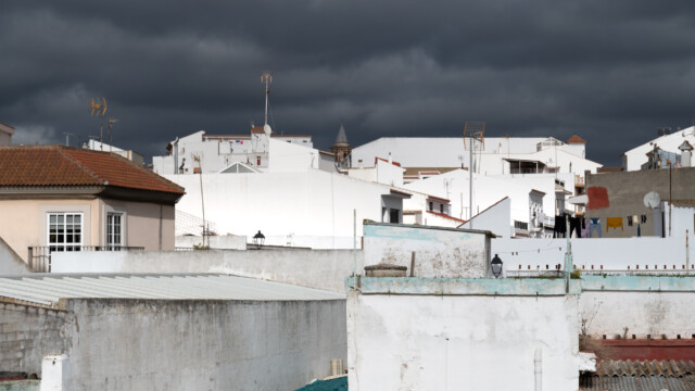 weisse Flachdachhäuserfront vor dunkeln Wolken