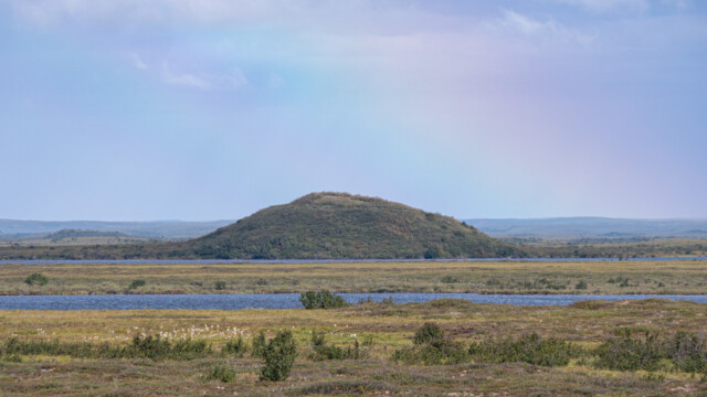 Pingo mit schwachem Regenbogen im Hintergrund