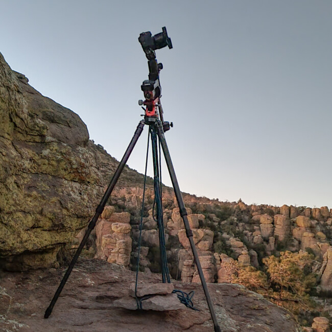 Stativ mit AstroausrĂĽstung, mit einem Seil an Steinplatten auf den Boden fixiert