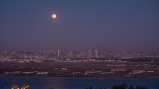 fast Vollmond über der Skyline von San Diego (die grüne Linie unter dem Mond ist ein Flugzeug)