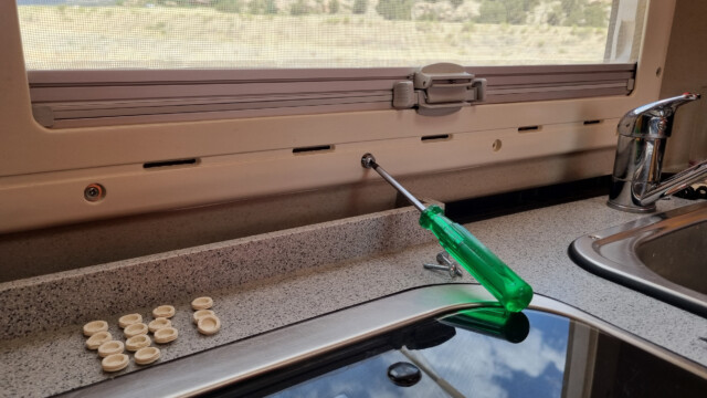 Gummiabdeckungen entfernen und Schrauben lösen